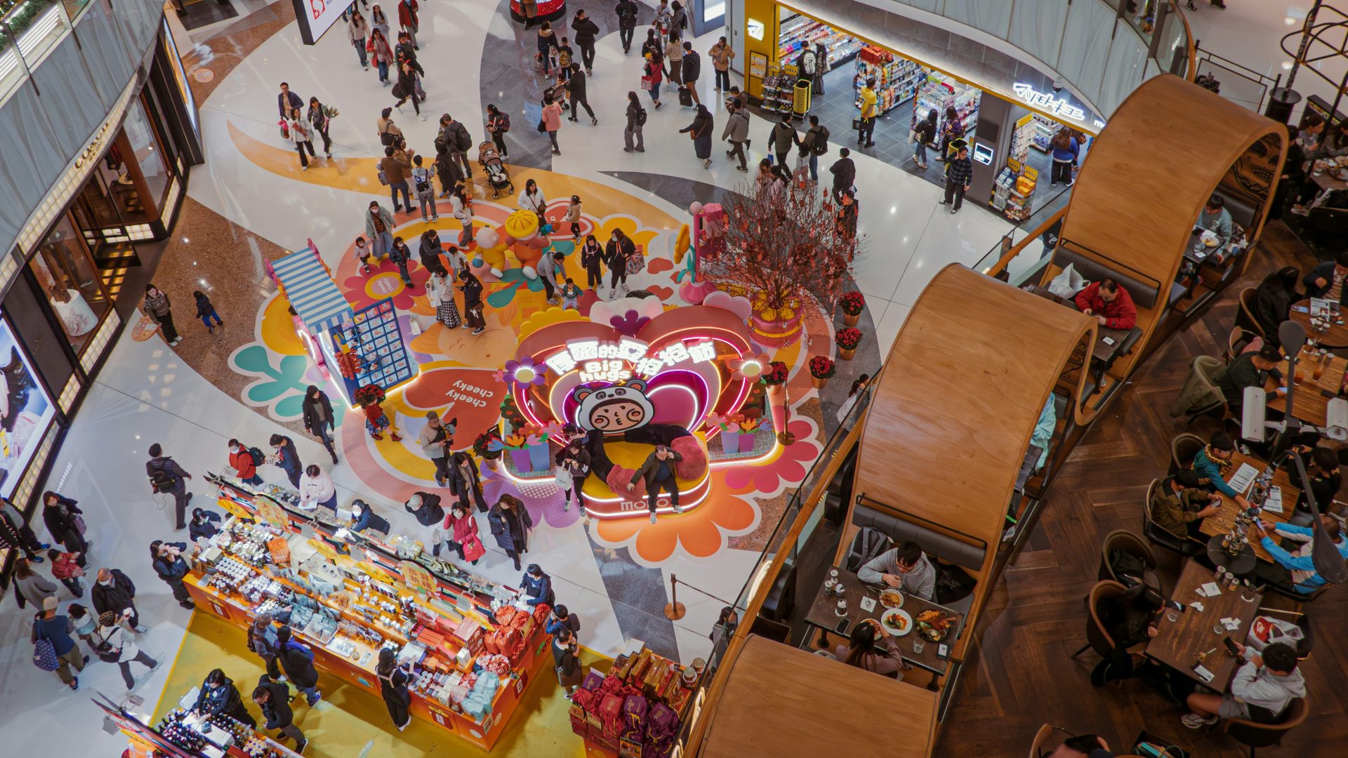 People shop and gather in a busy, colorful mall.