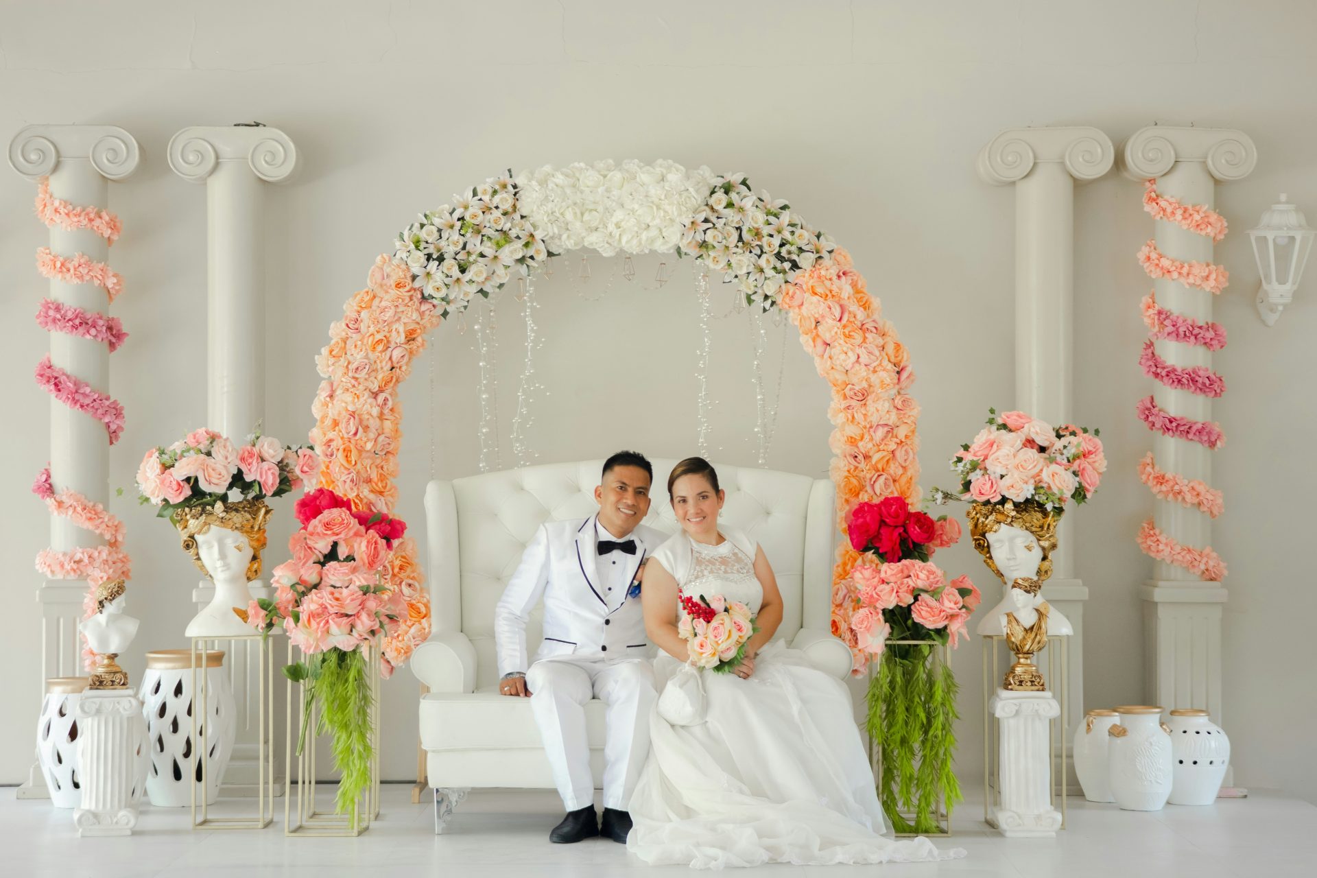 a bride and groom posing for a picture in front of a floral arch